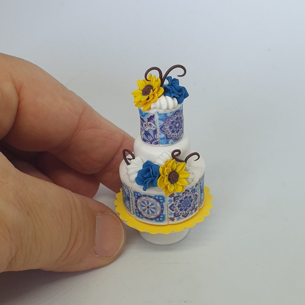 One inch scale wedding cake decorated in blue tiles style , part of the miniature workshop table
